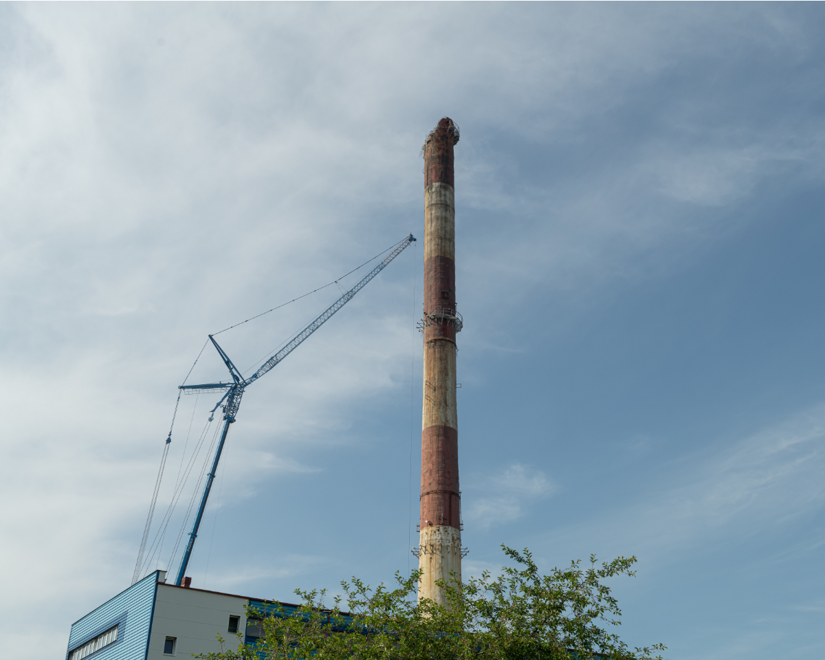 Komin Ciepłowni Południe na początku rozbiórki. Obok widzimy dźwig, który używany jest do demontażu komina. 