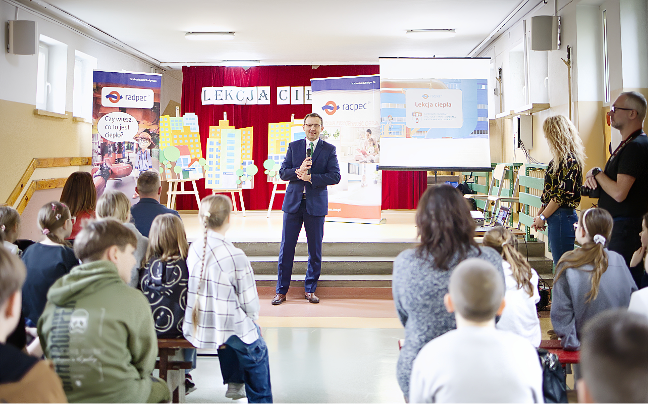 Prezes RADPEC-u Tomasz Nita stoi z mikrofonem przed uczniami w trakcie podsumowania III edycji kampanii proekologicznej pn. „Lekcje ciepła” w Publicznej Szkole Podstawowej nr 3 w Radomiu.